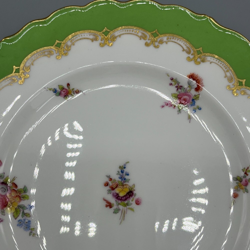 A pair of Victorian Coalport porcelain plates with bright green scalloped borders, gilded scrollwork, and hand-painted floral sprays on white centres. View VII