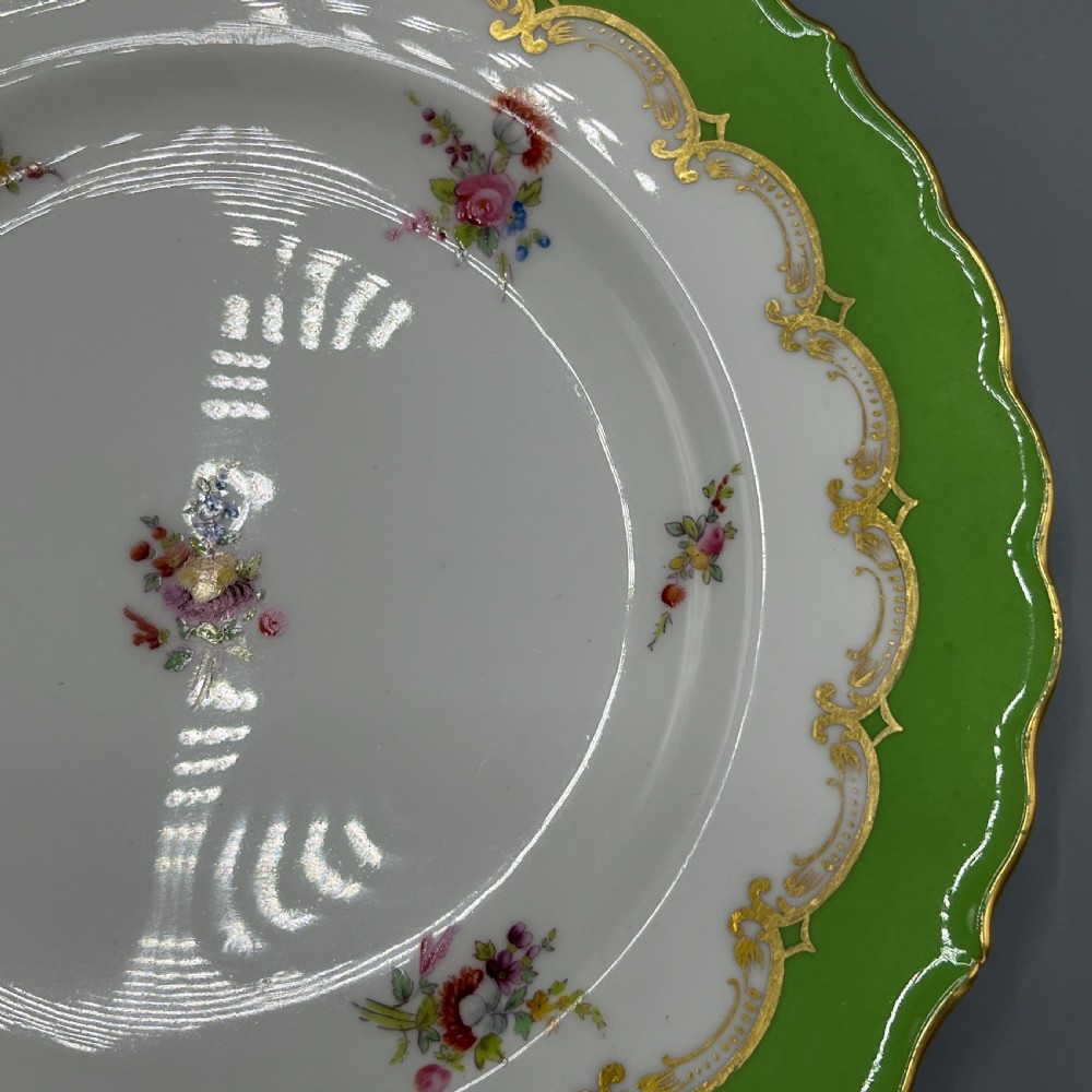 A pair of Victorian Coalport porcelain plates with bright green scalloped borders, gilded scrollwork, and hand-painted floral sprays on white centres. View VIII