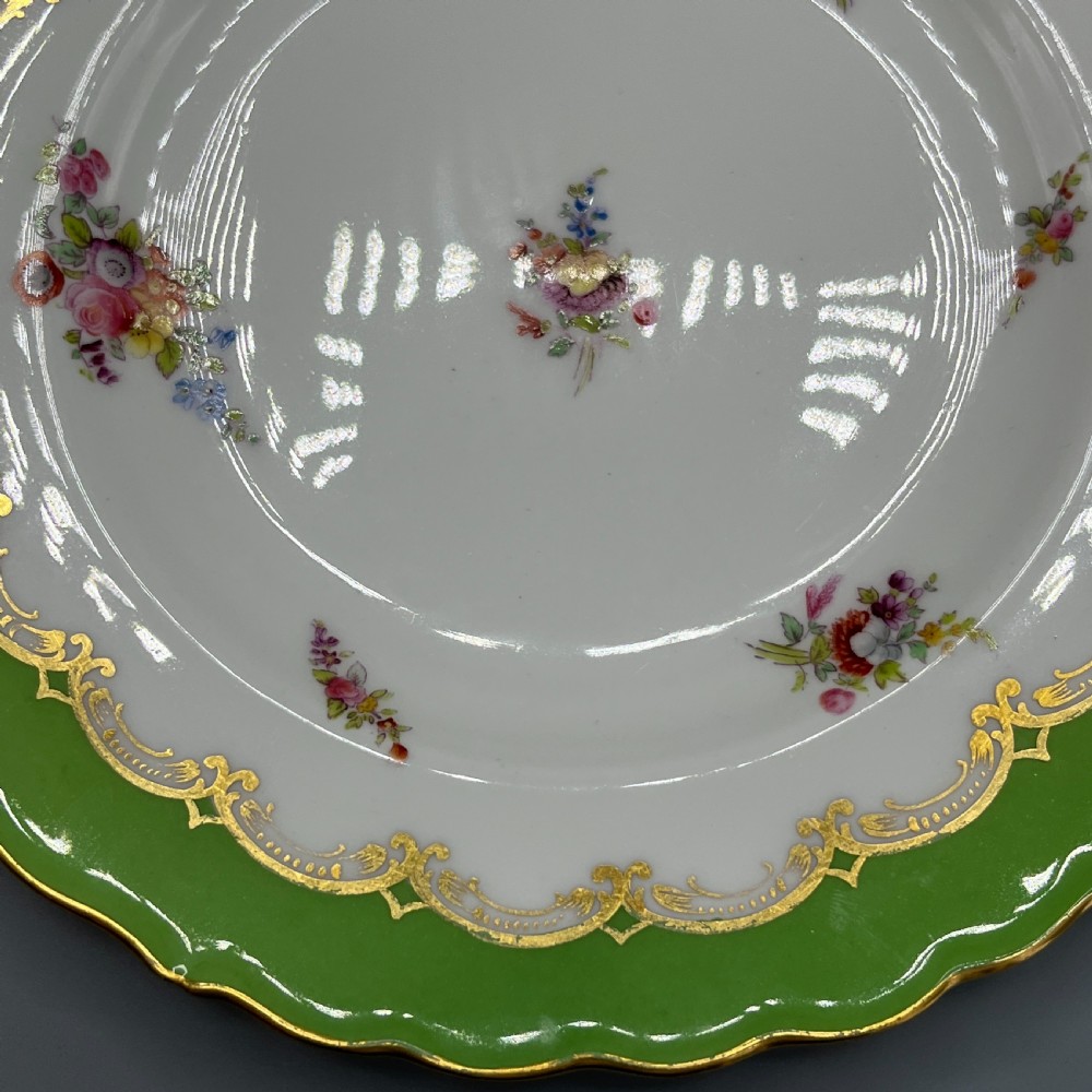 A pair of Victorian Coalport porcelain plates with bright green scalloped borders, gilded scrollwork, and hand-painted floral sprays on white centres. View IX