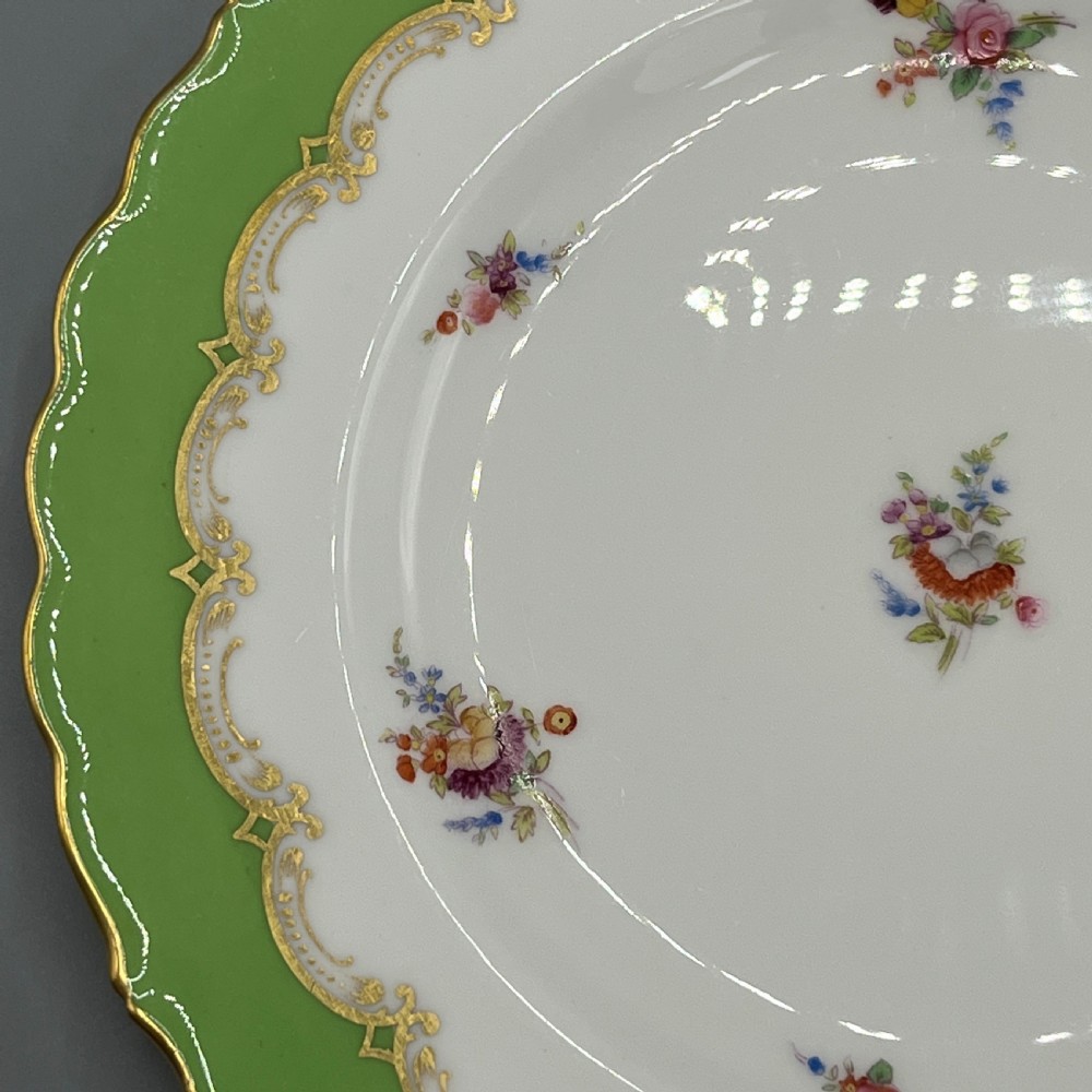 A pair of Victorian Coalport porcelain plates with bright green scalloped borders, gilded scrollwork, and hand-painted floral sprays on white centres. View XII