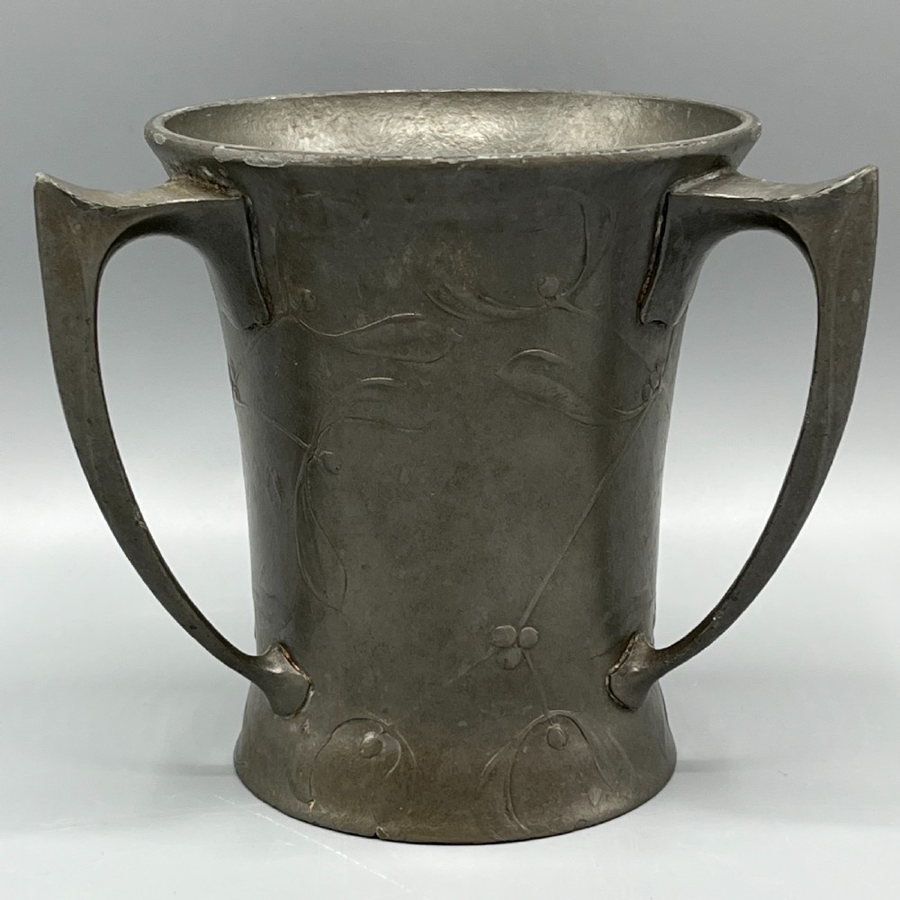 A grey pewter Art Nouveau tyg vase featuring three curved handles and relief-moulded mistletoe motifs around the body. View IV