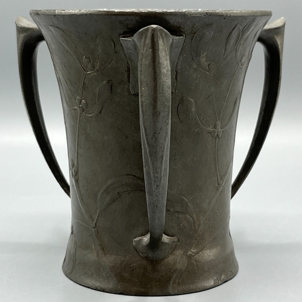 A grey pewter Art Nouveau tyg vase featuring three curved handles and relief-moulded mistletoe motifs around the body. View V