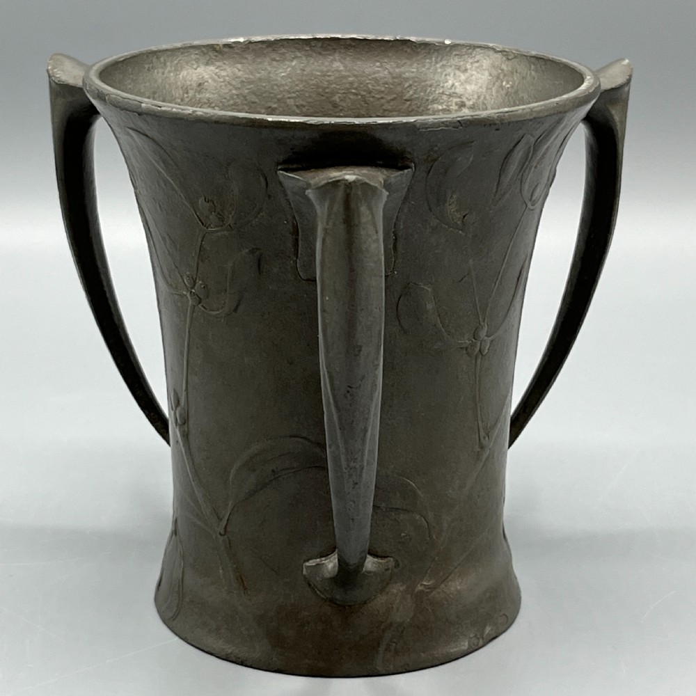 A grey pewter Art Nouveau tyg vase featuring three curved handles and relief-moulded mistletoe motifs around the body. View VI