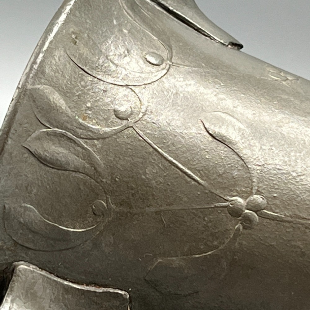 A grey pewter Art Nouveau tyg vase featuring three curved handles and relief-moulded mistletoe motifs around the body. View X
