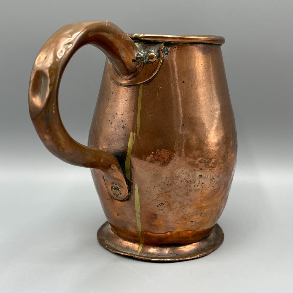 An antique Georgian copper jug featuring a hand-hammered body, wide pouring spout, flared base, and a riveted loop handle. View III