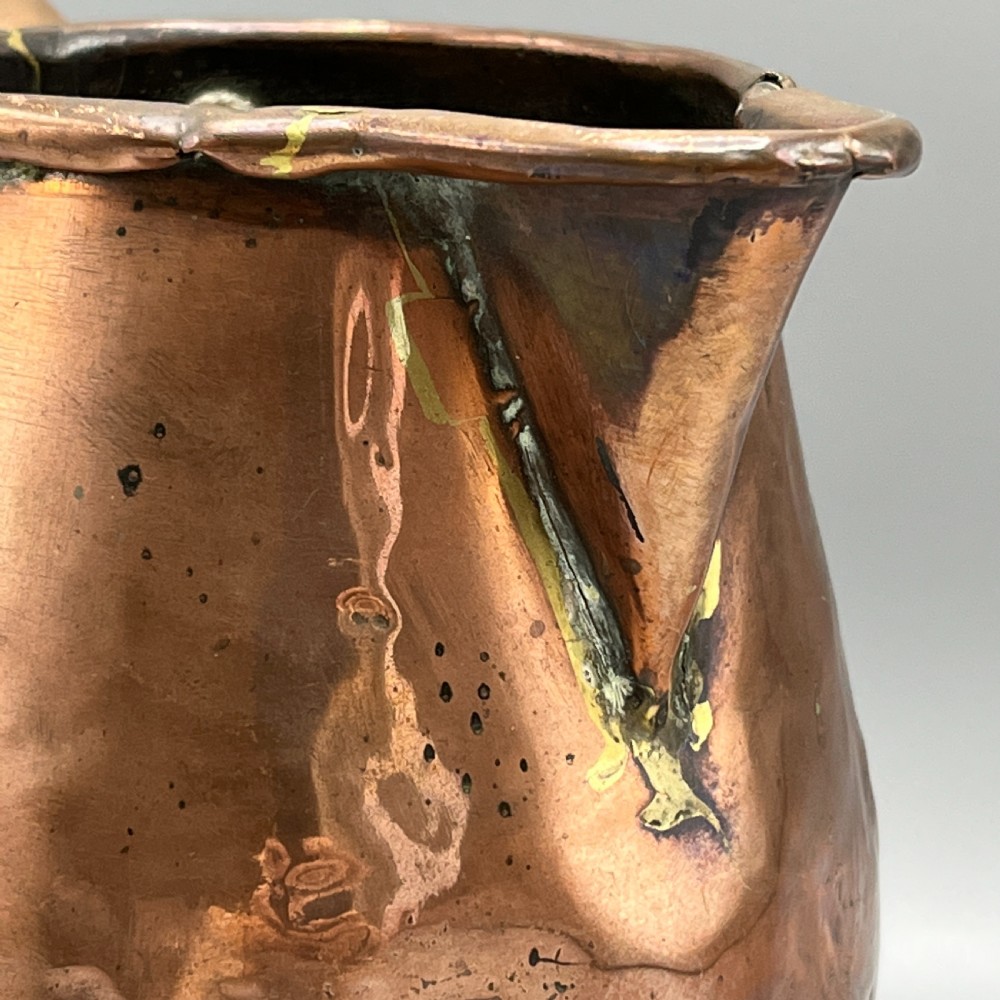 An antique Georgian copper jug featuring a hand-hammered body, wide pouring spout, flared base, and a riveted loop handle. View VIII