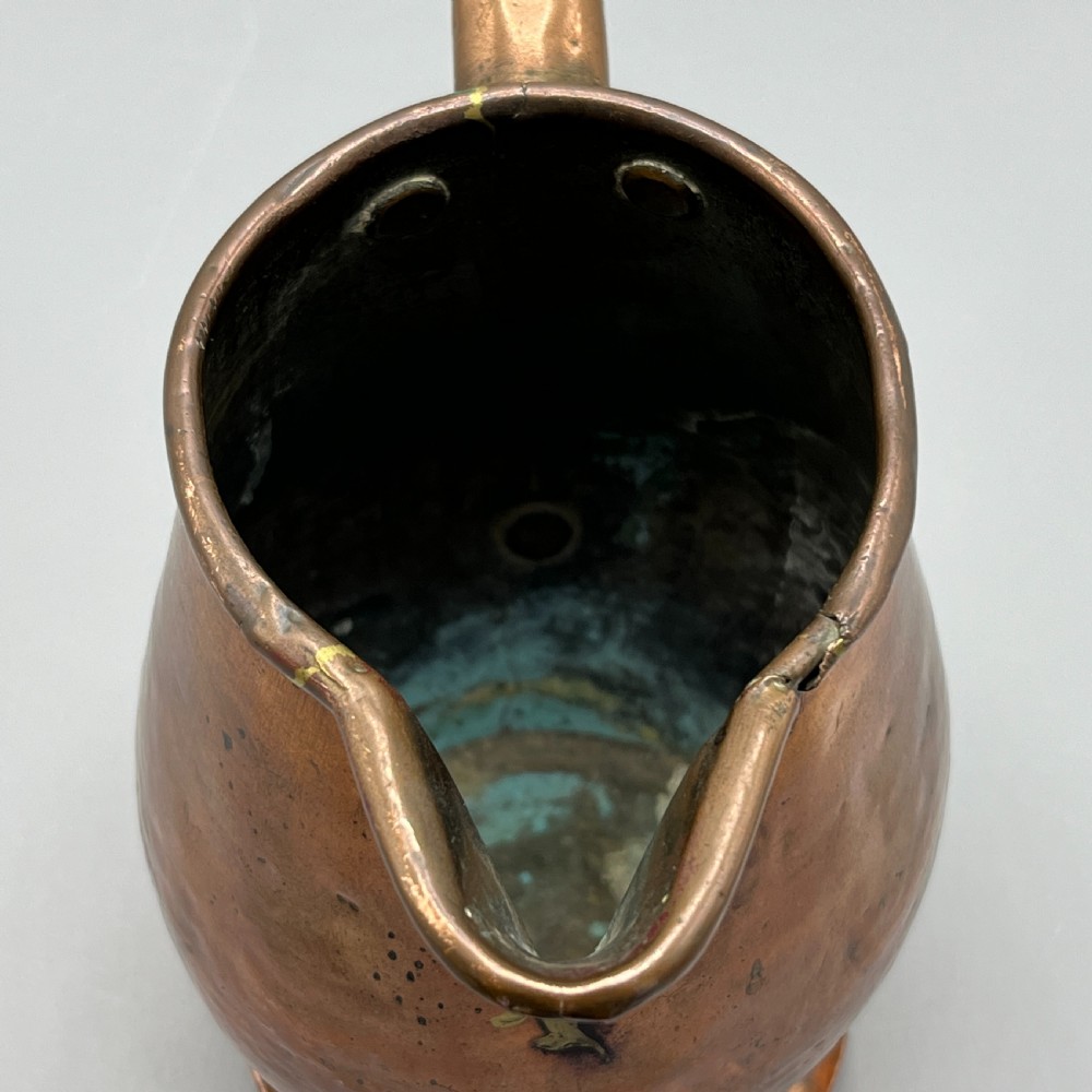 An antique Georgian copper jug featuring a hand-hammered body, wide pouring spout, flared base, and a riveted loop handle. View XVI