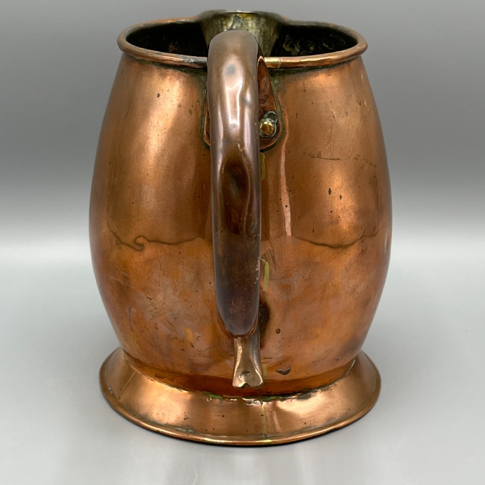 A Georgian copper jug featuring a bulbous body, a flared circular base, a pinched pouring spout, and a large curved loop handle. View V