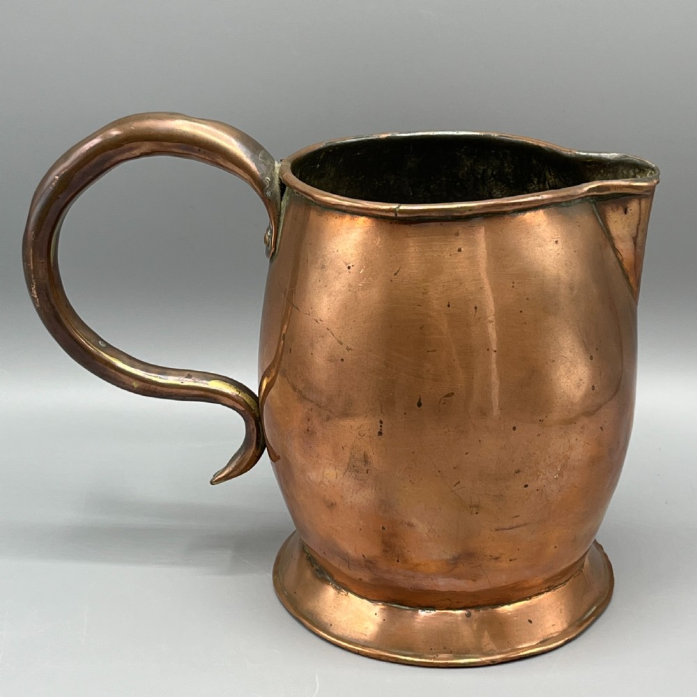 A Georgian copper jug featuring a bulbous body, a flared circular base, a pinched pouring spout, and a large curved loop handle. View IX
