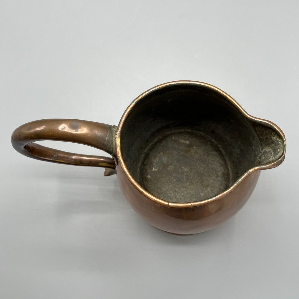 A Georgian copper jug featuring a bulbous body, a flared circular base, a pinched pouring spout, and a large curved loop handle. View XV
