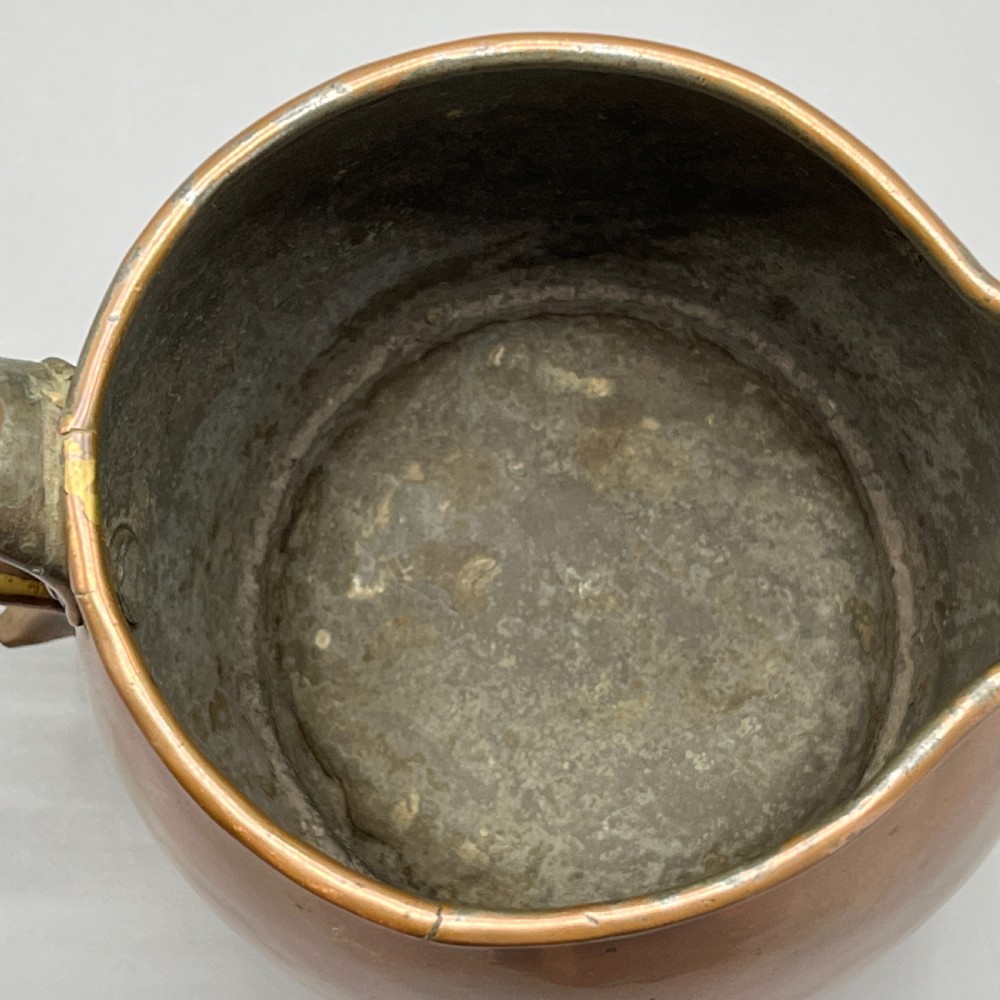 A Georgian copper jug featuring a bulbous body, a flared circular base, a pinched pouring spout, and a large curved loop handle. View XVI