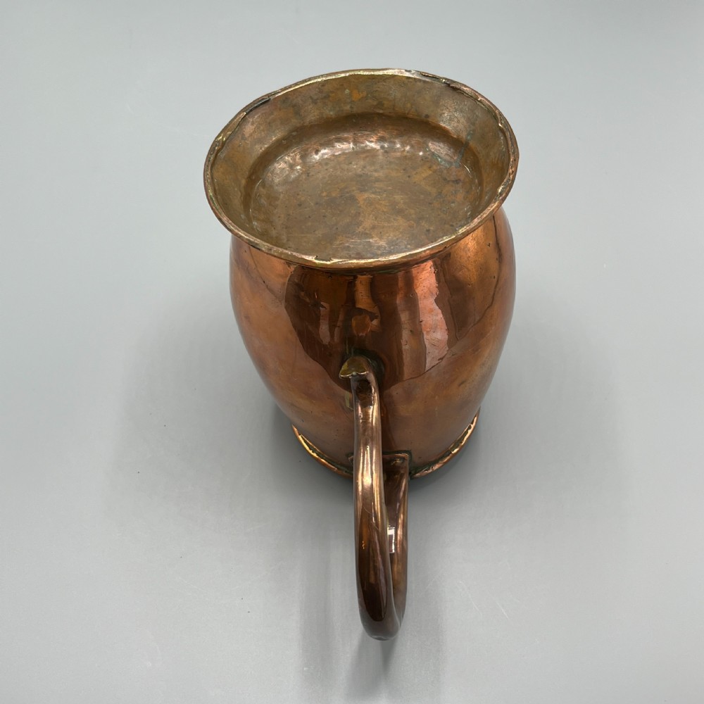 A Georgian copper jug featuring a bulbous body, a flared circular base, a pinched pouring spout, and a large curved loop handle. View XVII