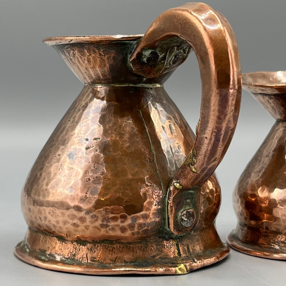 A set of three graduated Victorian copper miniature jugs with hand-hammered surfaces and flared spouts. View XIII