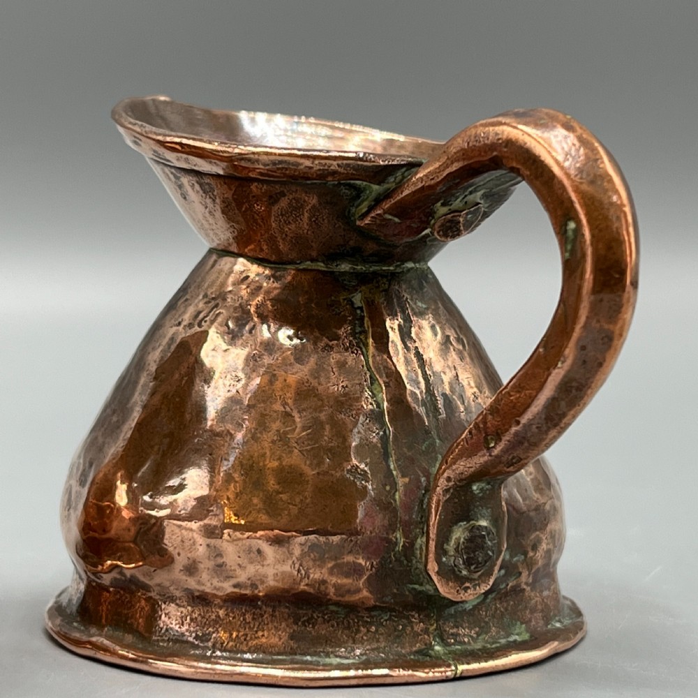 A set of three graduated Victorian copper miniature jugs with hand-hammered surfaces and flared spouts. View XV