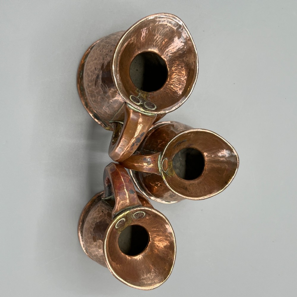 A set of three graduated Victorian copper miniature jugs with hand-hammered surfaces and flared spouts. View XVII