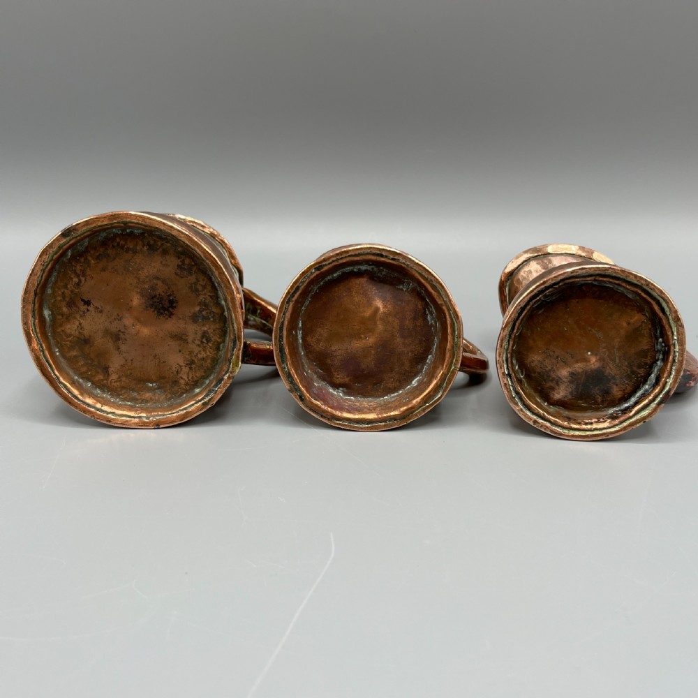 A set of three graduated Victorian copper miniature jugs with hand-hammered surfaces and flared spouts. View XIX