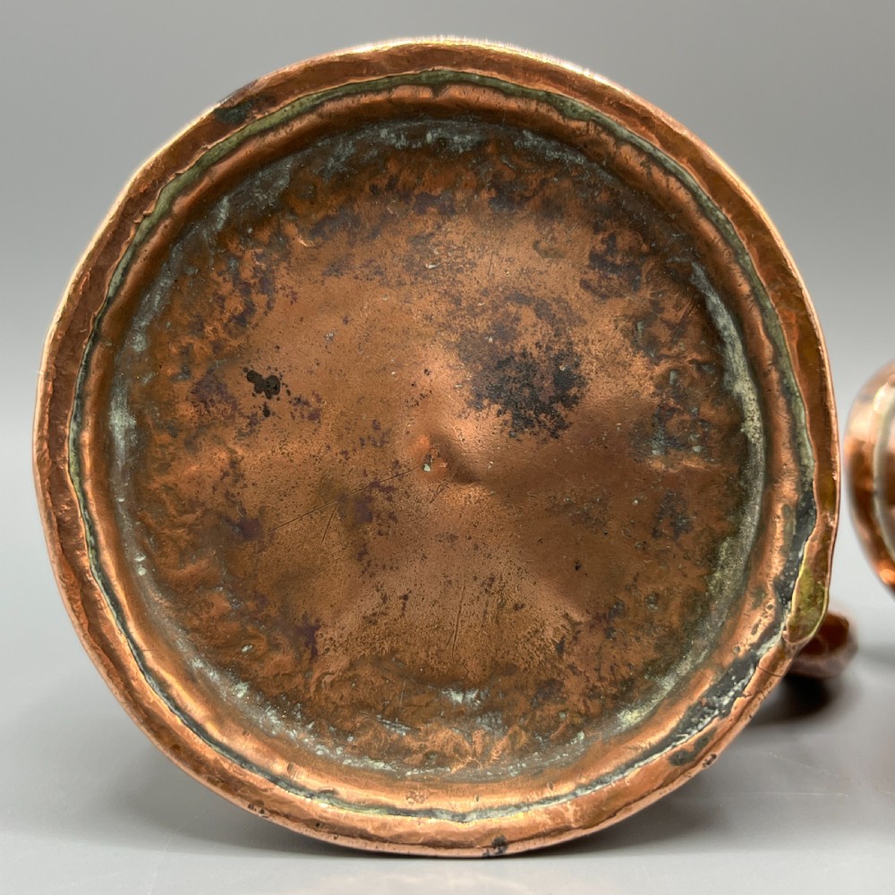 A set of three graduated Victorian copper miniature jugs with hand-hammered surfaces and flared spouts. View XX