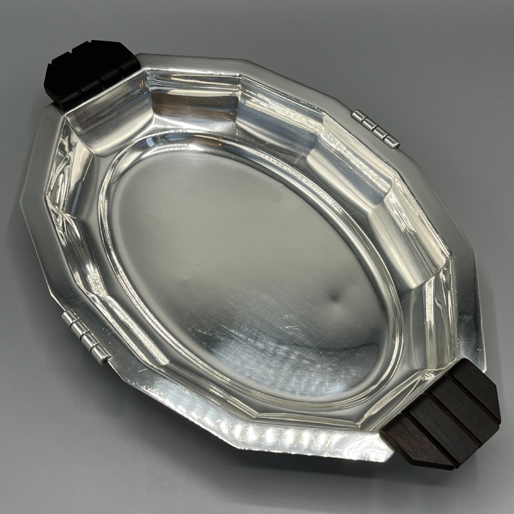 An octagonal silver-plated serving dish featuring faceted sides and carved dark wooden handles on opposite ends. View II