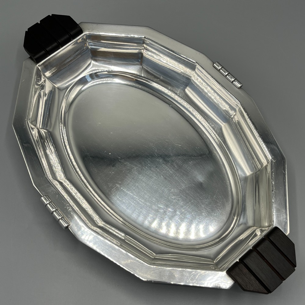 An octagonal silver-plated serving dish featuring faceted sides and carved dark wooden handles on opposite ends. View III