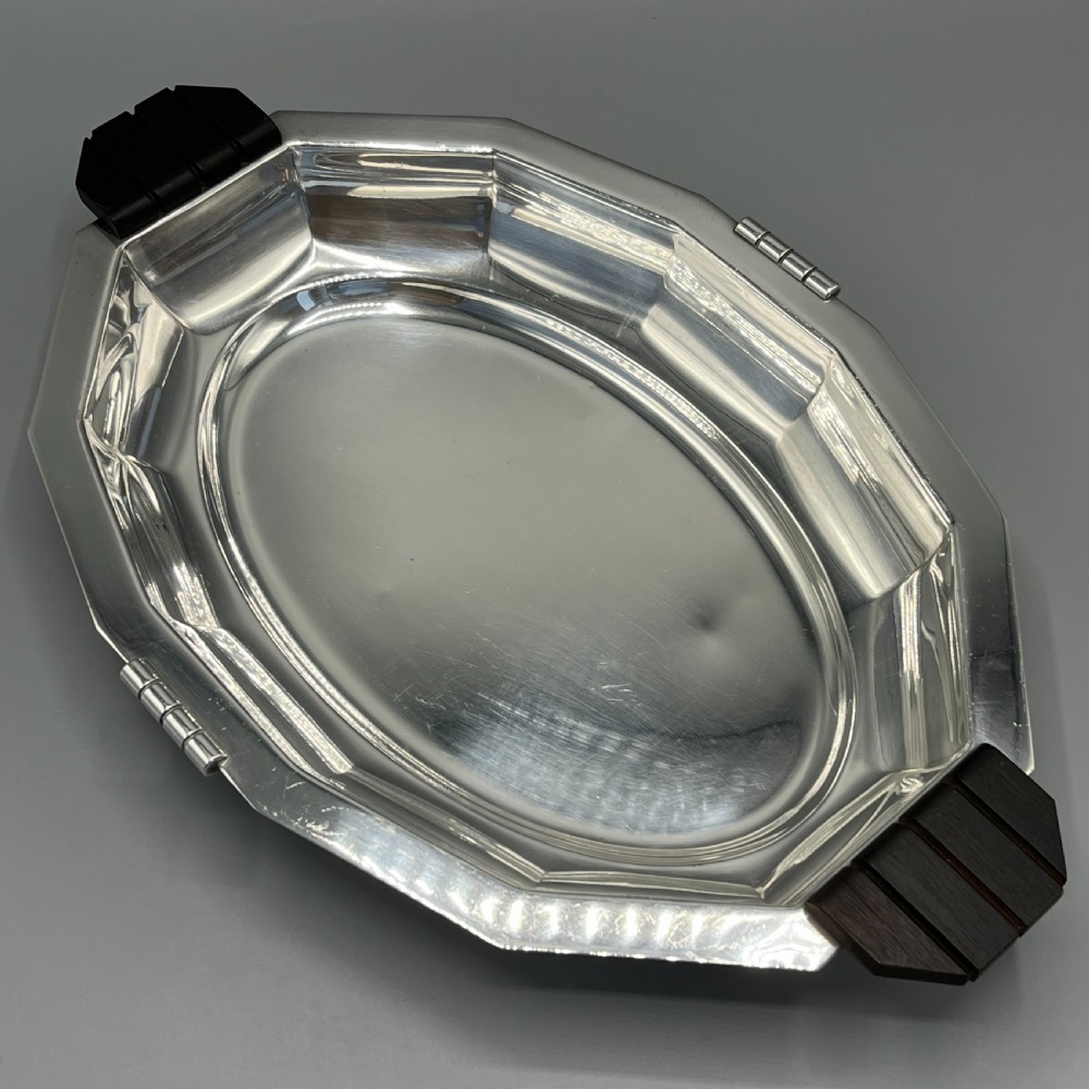 An octagonal silver-plated serving dish featuring faceted sides and carved dark wooden handles on opposite ends. View V
