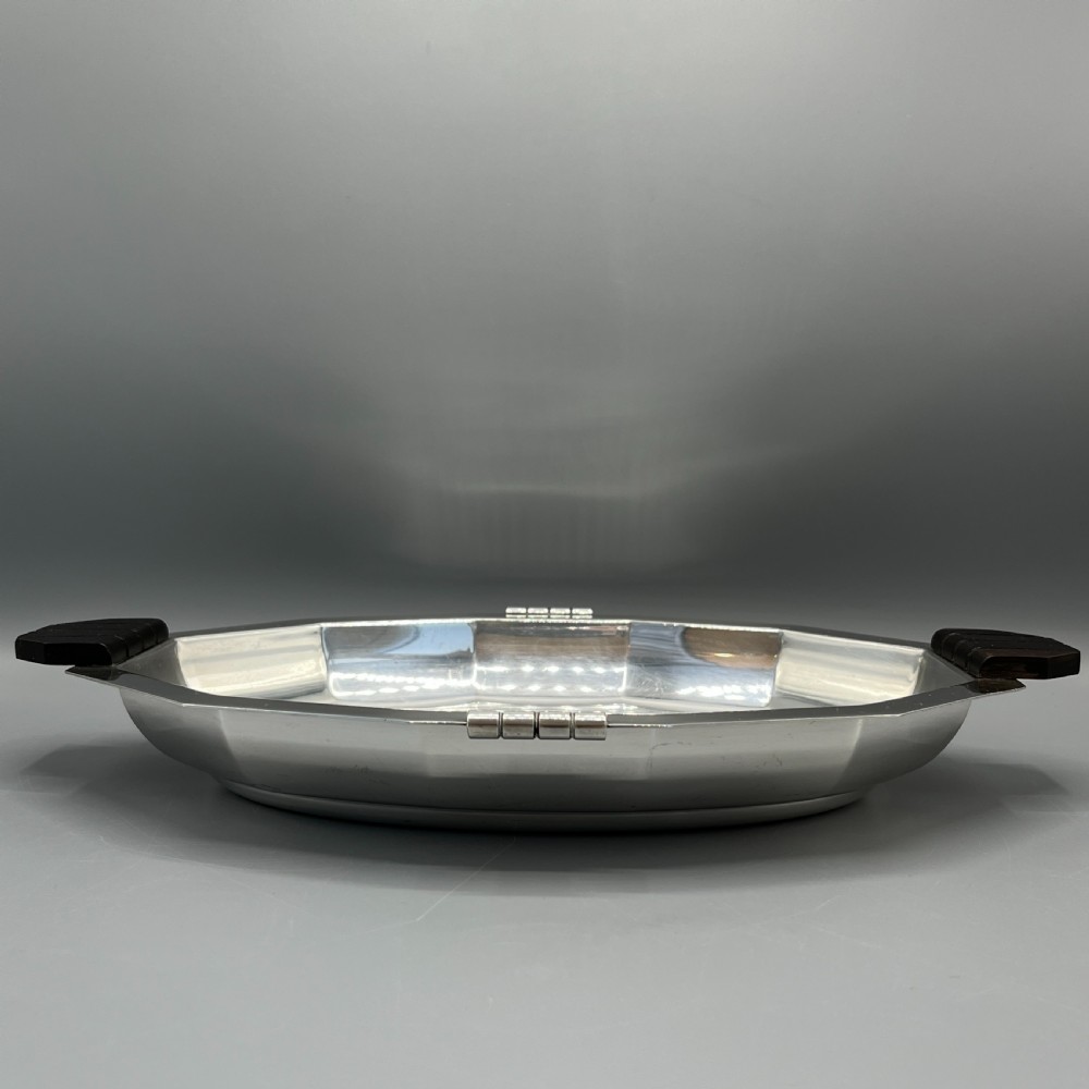 An octagonal silver-plated serving dish featuring faceted sides and carved dark wooden handles on opposite ends. View VII