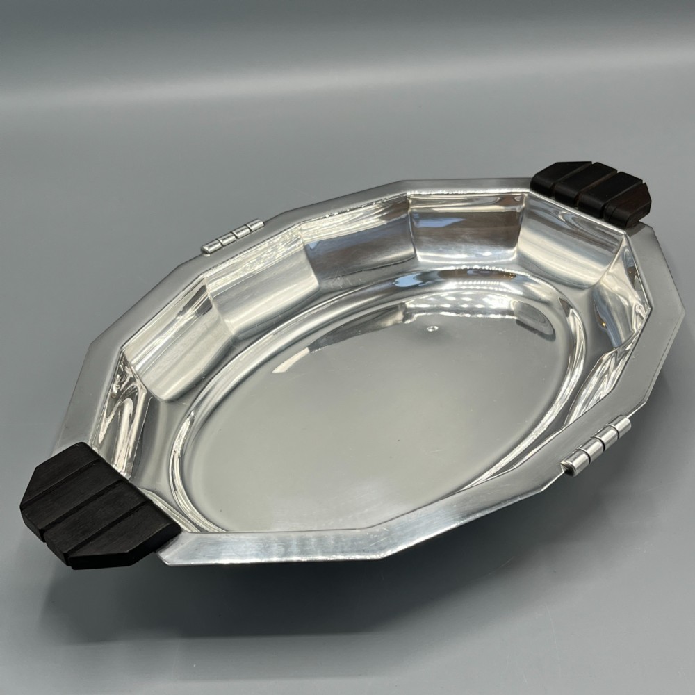 An octagonal silver-plated serving dish featuring faceted sides and carved dark wooden handles on opposite ends. View IX