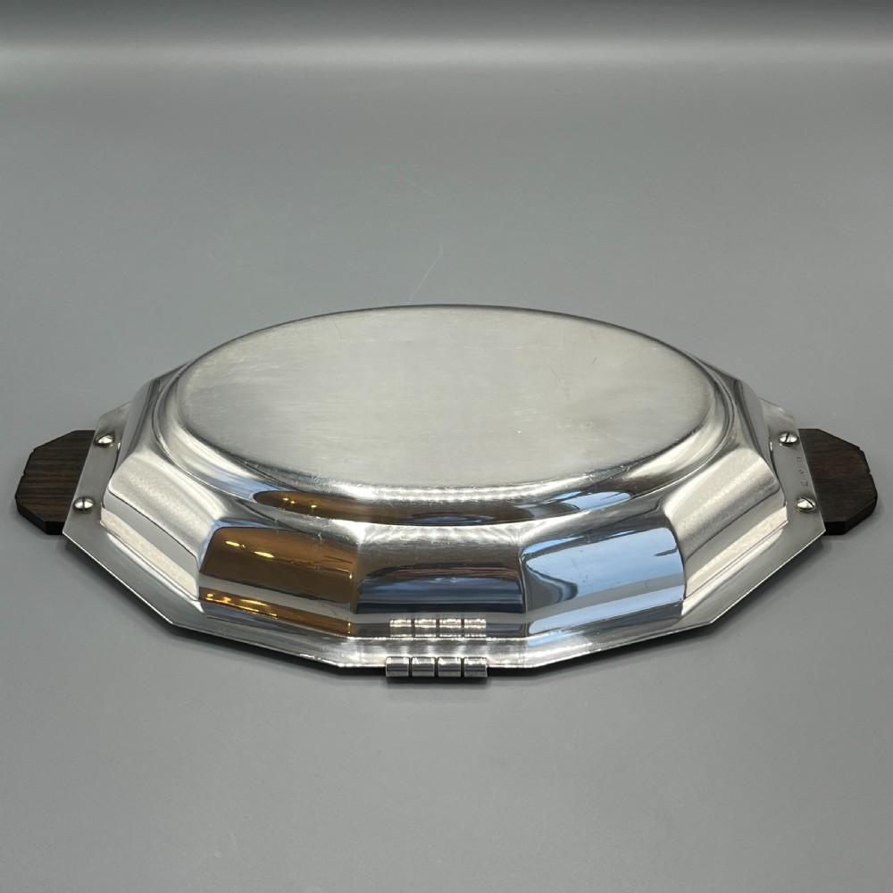 An octagonal silver-plated serving dish featuring faceted sides and carved dark wooden handles on opposite ends. View X