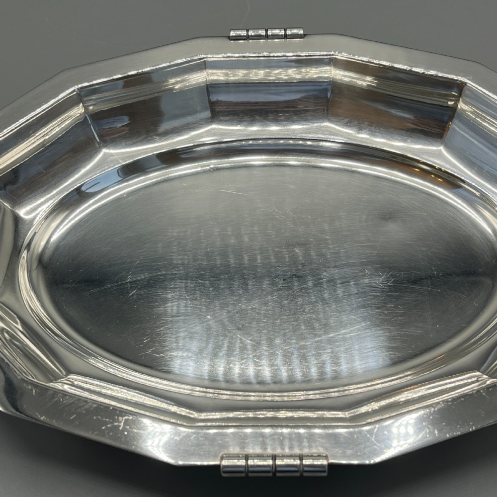 An octagonal silver-plated serving dish featuring faceted sides and carved dark wooden handles on opposite ends. View XIV