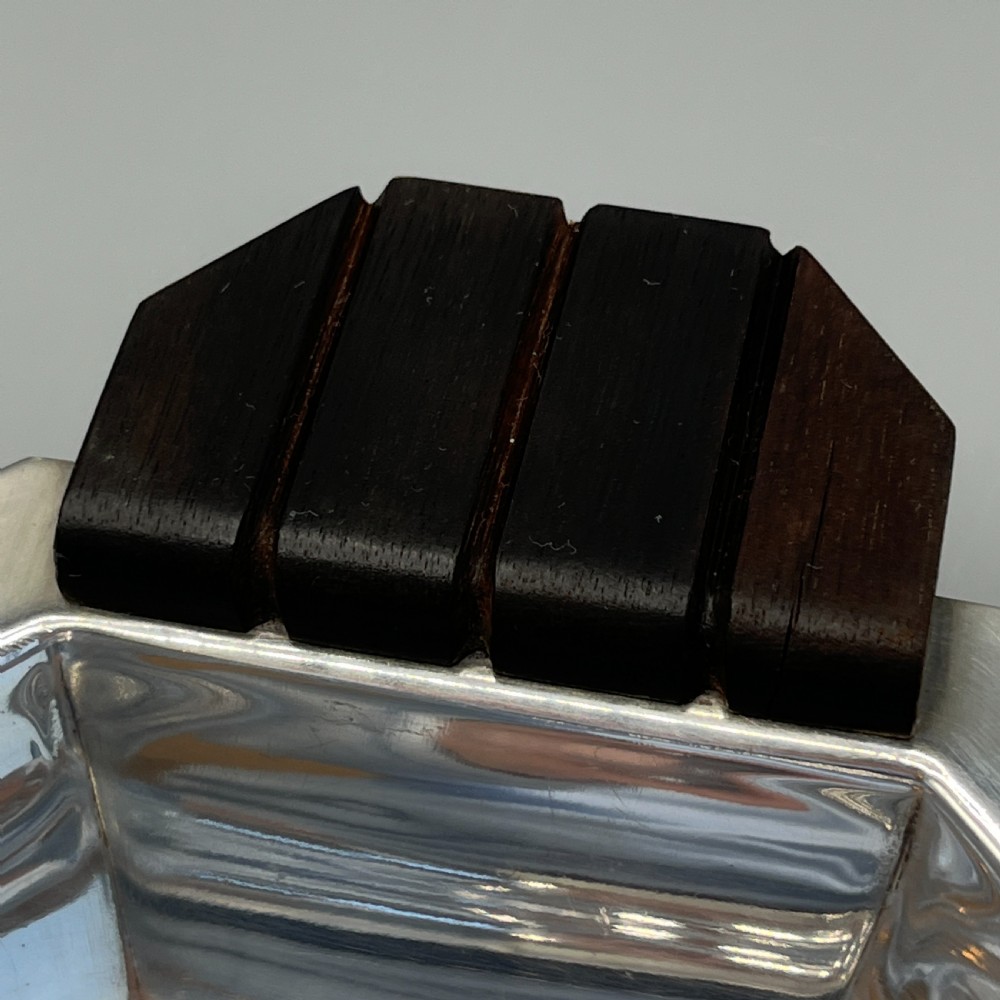 An octagonal silver-plated serving dish featuring faceted sides and carved dark wooden handles on opposite ends. View XVI