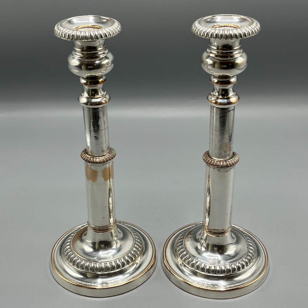 A pair of silver plated telescopic candlesticks featuring gadrooned borders and circular stepped bases.