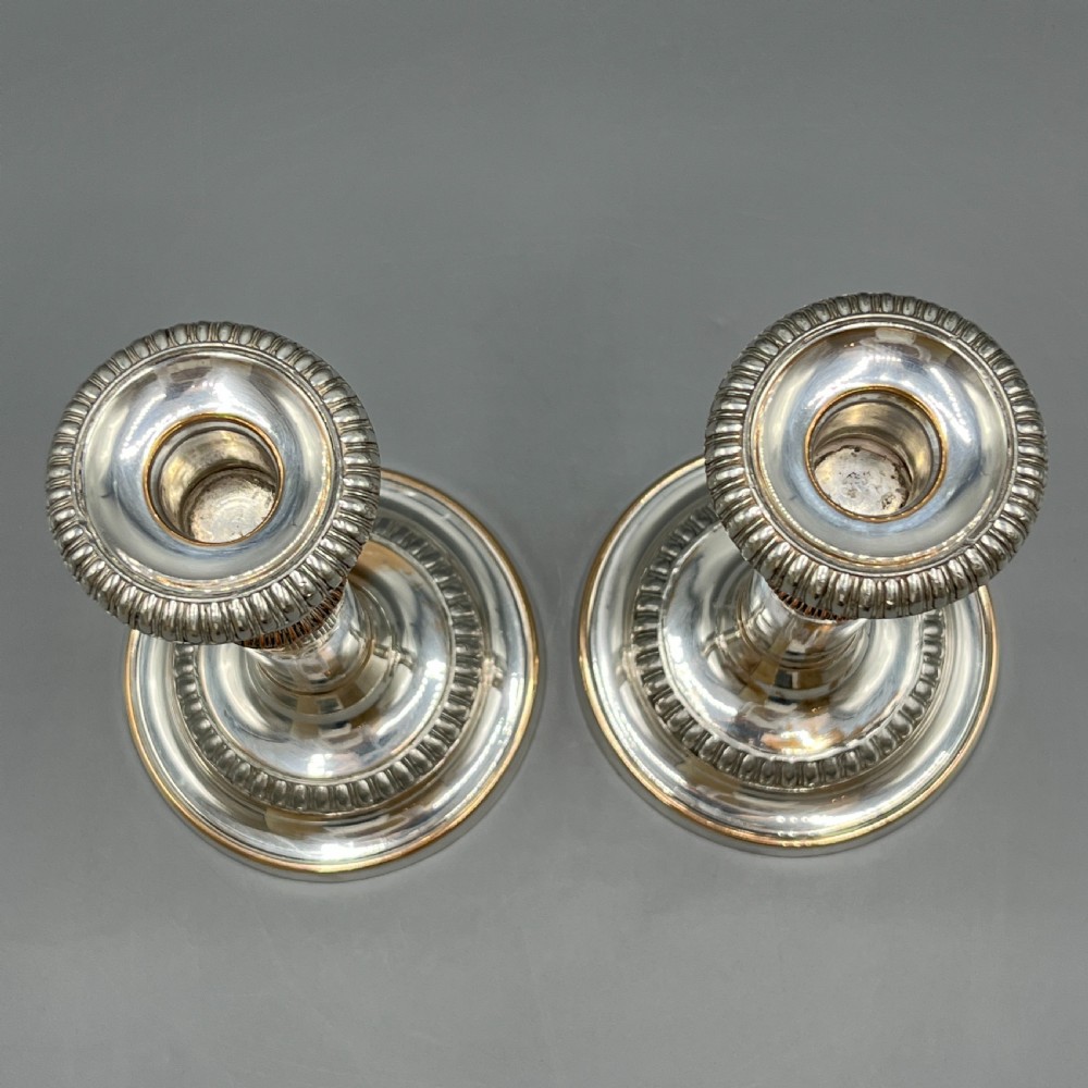 A pair of silver plated telescopic candlesticks featuring gadrooned borders and circular stepped bases. View X
