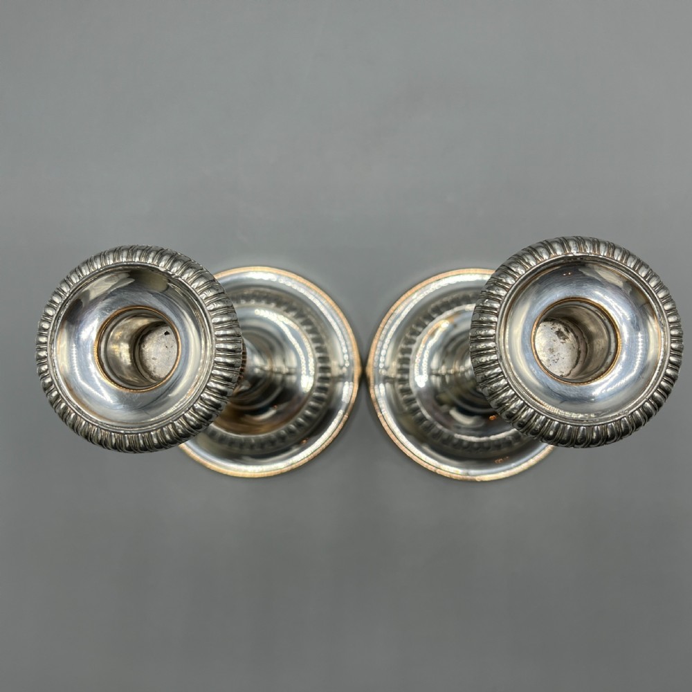 A pair of silver plated telescopic candlesticks featuring gadrooned borders and circular stepped bases. View XVIII