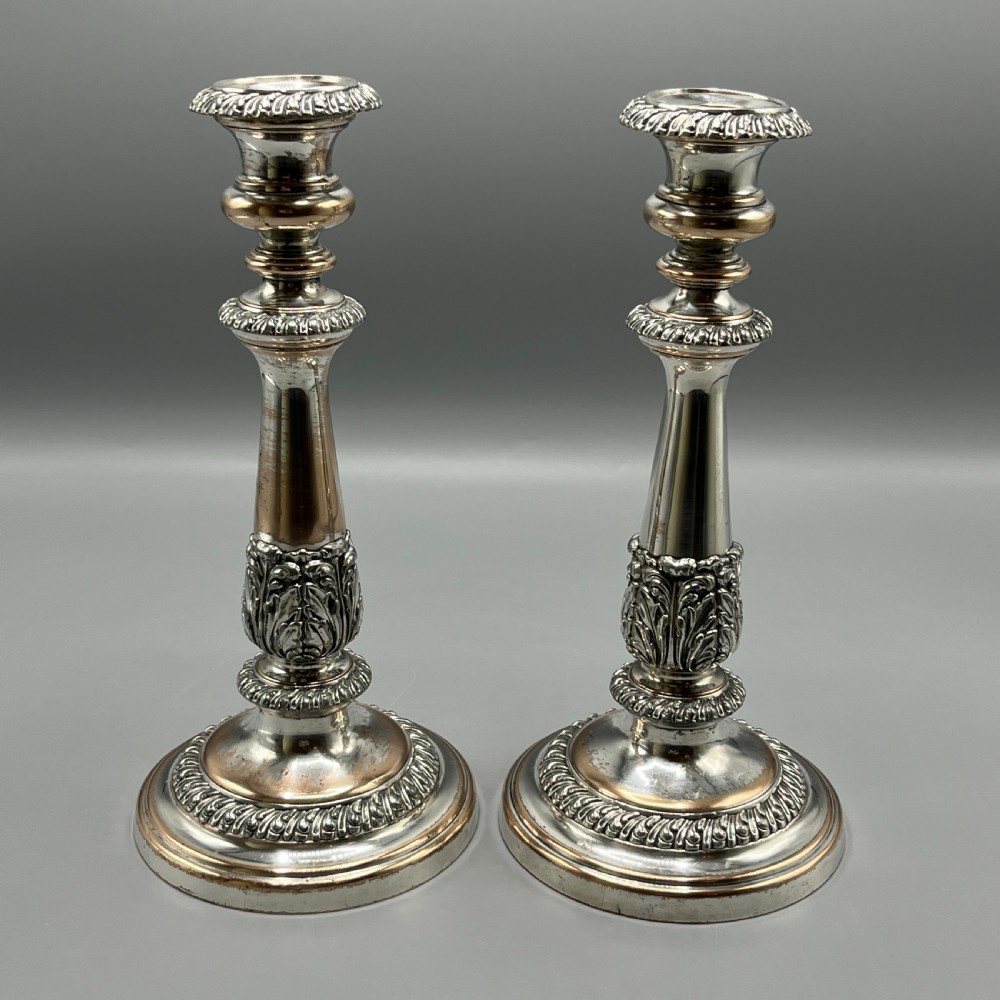 A pair of antique silver-plated candlesticks with gadrooned rims, acanthus leaf details, and exposed copper highlights on round bases. View II
