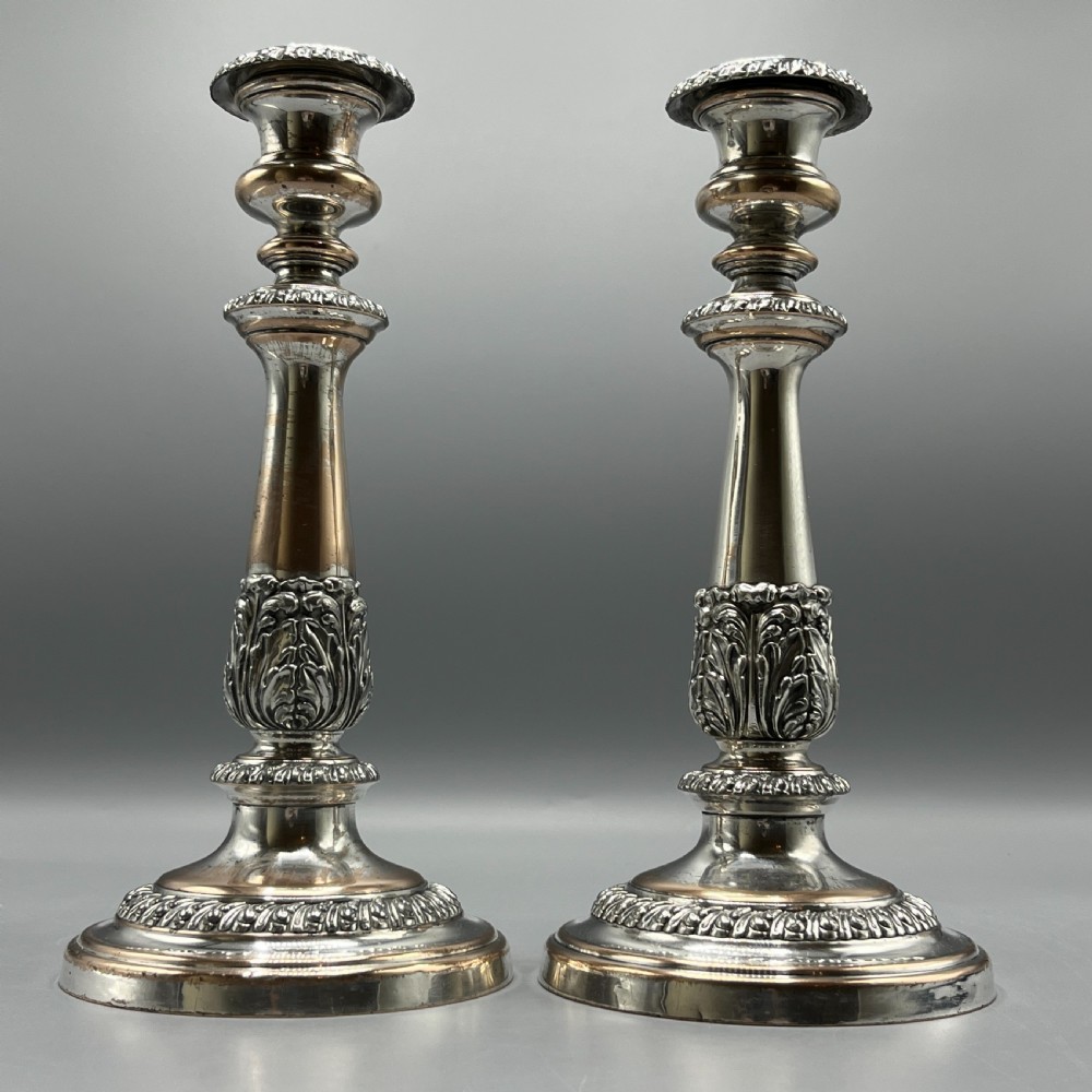 A pair of antique silver-plated candlesticks with gadrooned rims, acanthus leaf details, and exposed copper highlights on round bases. View III