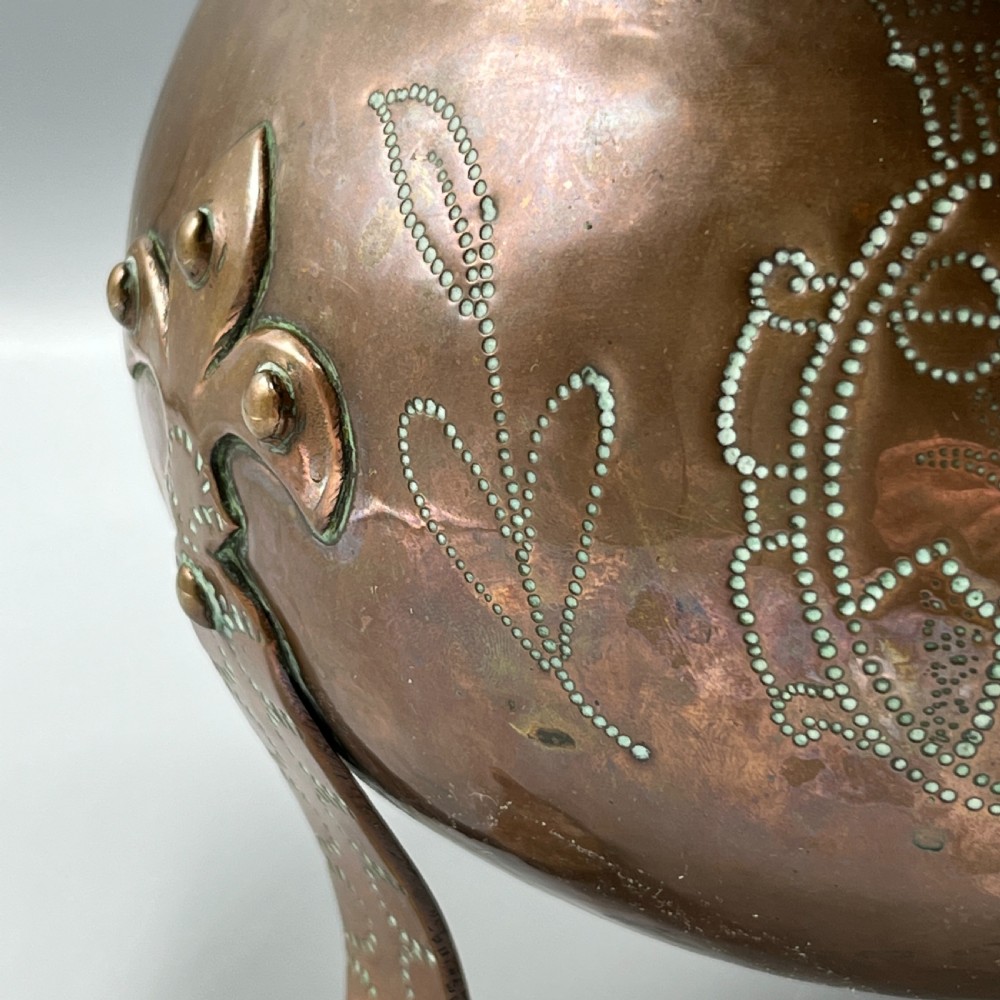 A solid copper Arts and Crafts jardiniere featuring a crimped ruffled rim, dot-punched floral motifs, and riveted splayed legs. View III