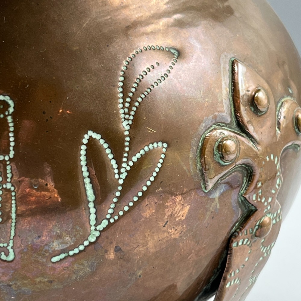 A solid copper Arts and Crafts jardiniere featuring a crimped ruffled rim, dot-punched floral motifs, and riveted splayed legs. View V