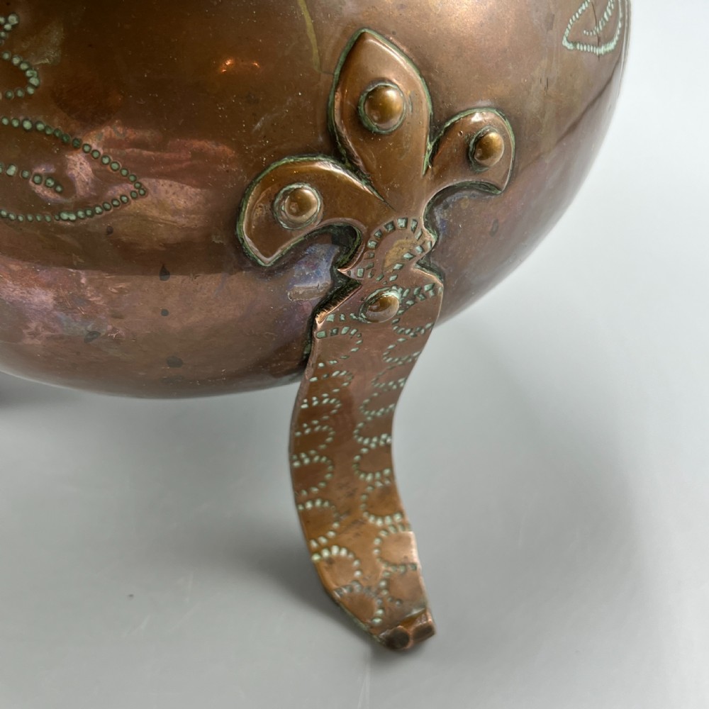 A solid copper Arts and Crafts jardiniere featuring a crimped ruffled rim, dot-punched floral motifs, and riveted splayed legs. View X