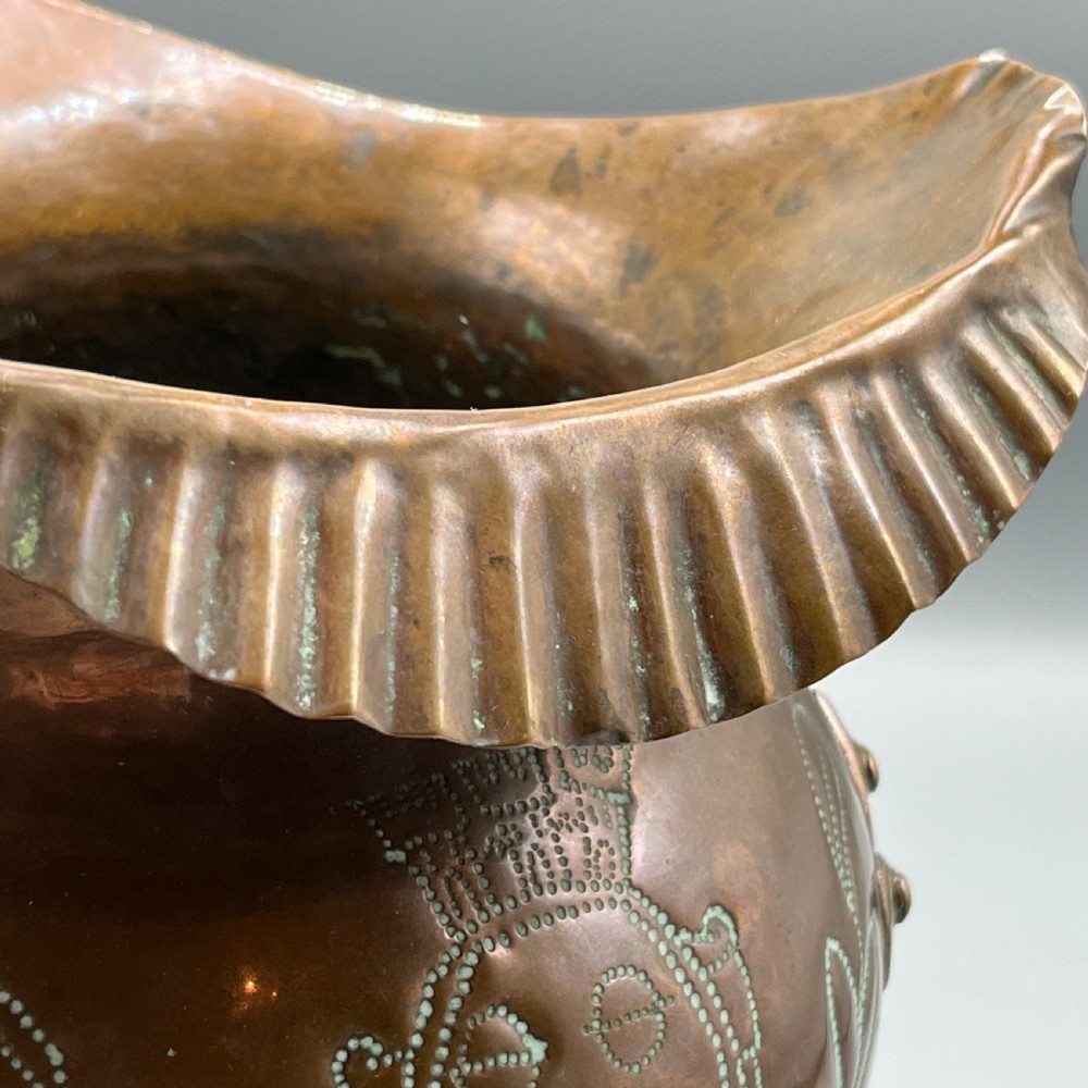 A solid copper Arts and Crafts jardiniere featuring a crimped ruffled rim, dot-punched floral motifs, and riveted splayed legs. View XIII