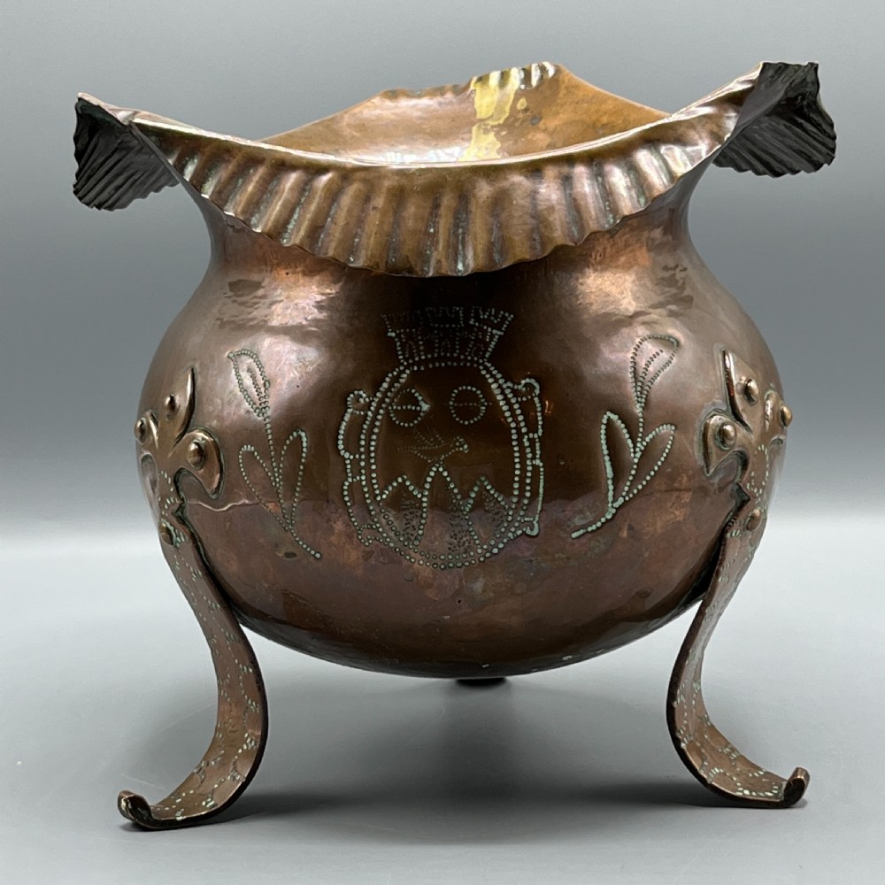 A solid copper Arts and Crafts jardiniere featuring a crimped ruffled rim, dot-punched floral motifs, and riveted splayed legs. View XIV
