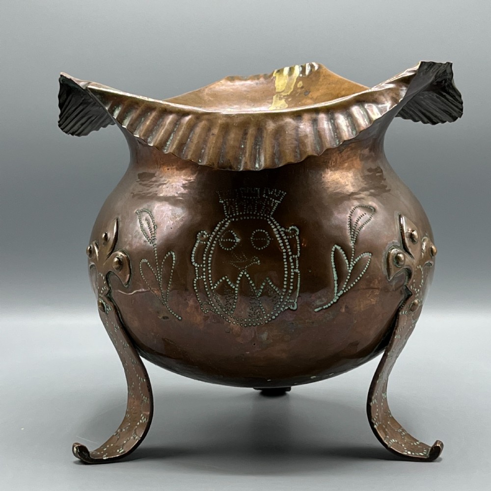 A solid copper Arts and Crafts jardiniere featuring a crimped ruffled rim, dot-punched floral motifs, and riveted splayed legs. View XV