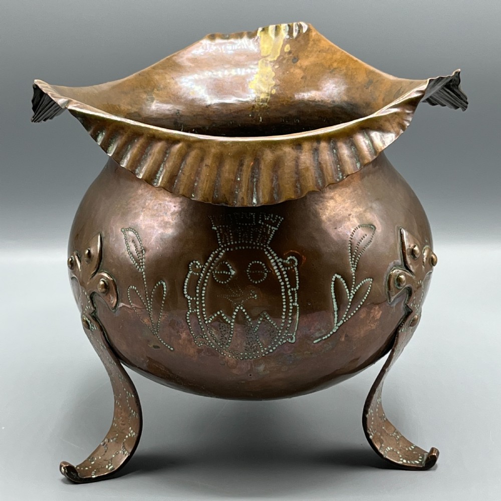 A solid copper Arts and Crafts jardiniere featuring a crimped ruffled rim, dot-punched floral motifs, and riveted splayed legs. View XVI