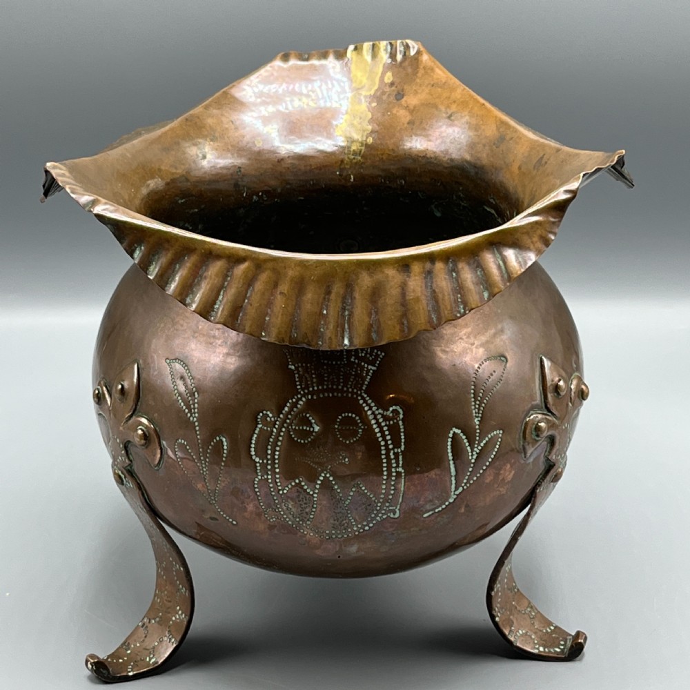 A solid copper Arts and Crafts jardiniere featuring a crimped ruffled rim, dot-punched floral motifs, and riveted splayed legs. View XVII