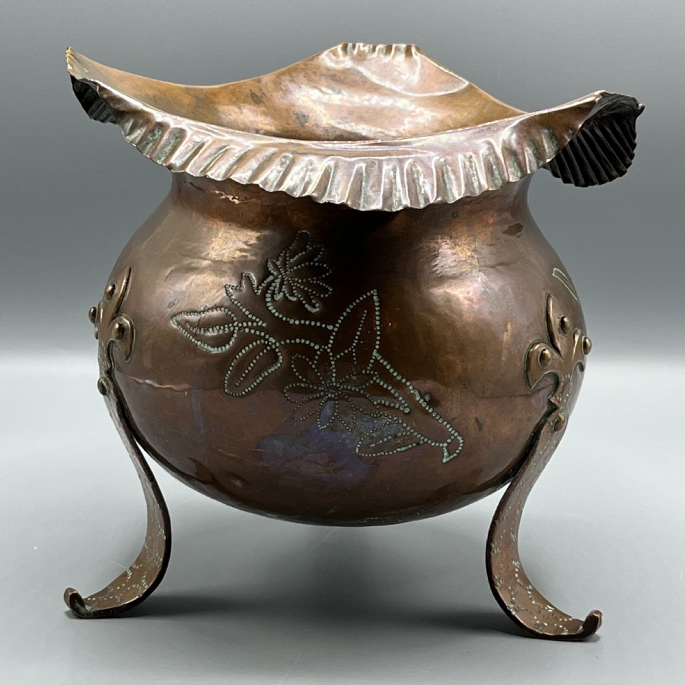 A solid copper Arts and Crafts jardiniere featuring a crimped ruffled rim, dot-punched floral motifs, and riveted splayed legs. View XVIII