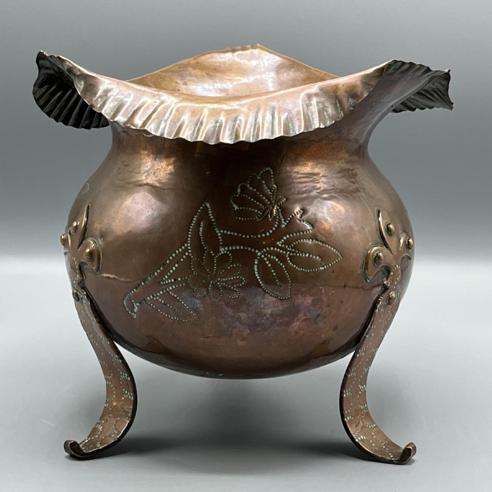A solid copper Arts and Crafts jardiniere featuring a crimped ruffled rim, dot-punched floral motifs, and riveted splayed legs. View XIX