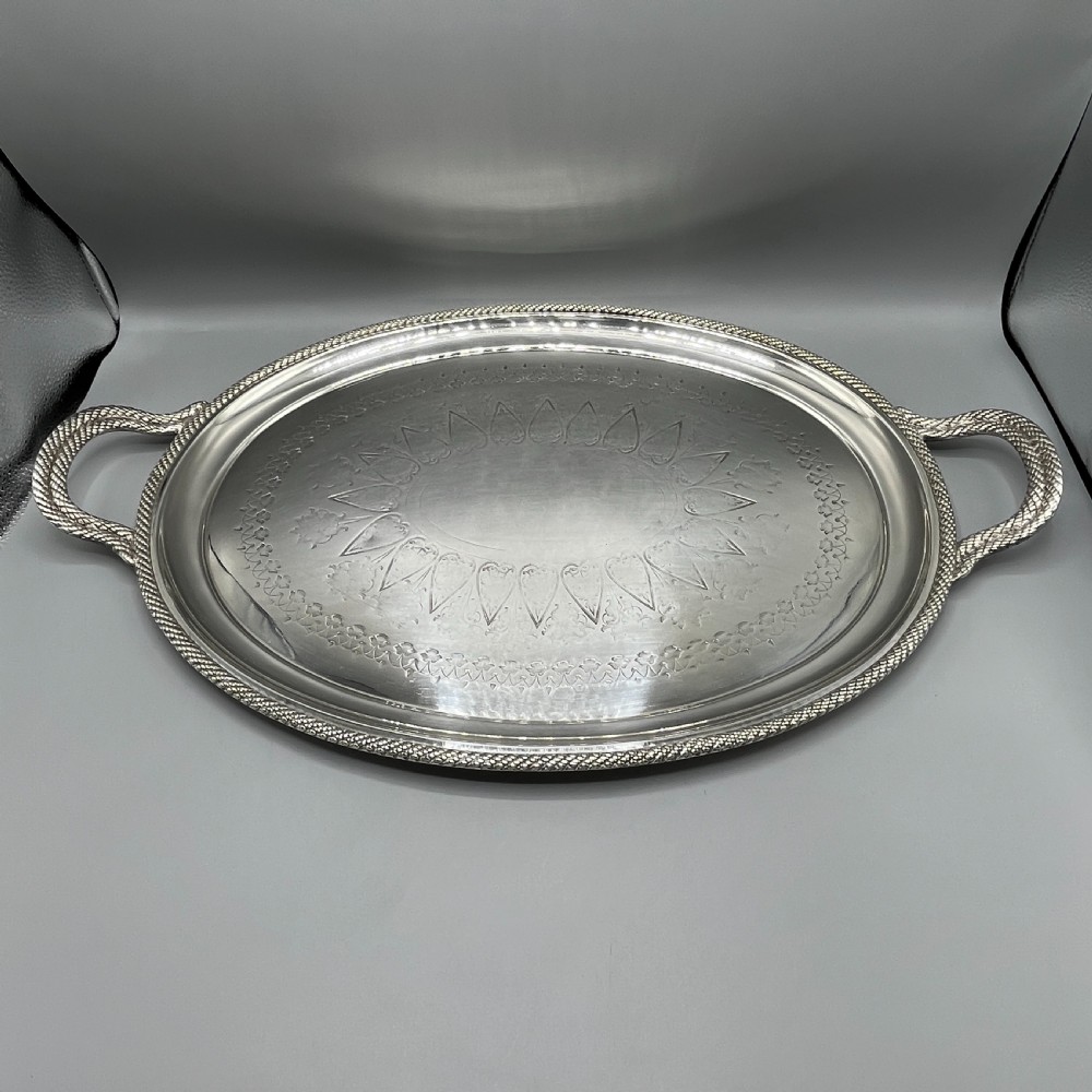 A large Victorian oval silver-plated serving tray featuring twin carrying handles, a textured rope border, and elaborate floral central engraving. View V