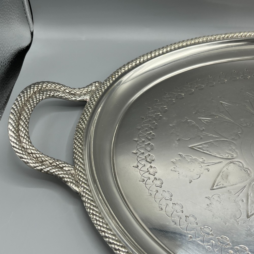 A large Victorian oval silver-plated serving tray featuring twin carrying handles, a textured rope border, and elaborate floral central engraving. View VI
