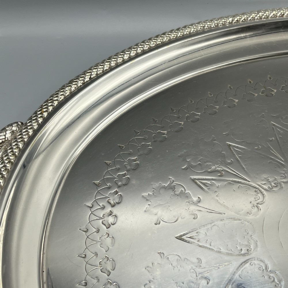 A large Victorian oval silver-plated serving tray featuring twin carrying handles, a textured rope border, and elaborate floral central engraving. View VIII