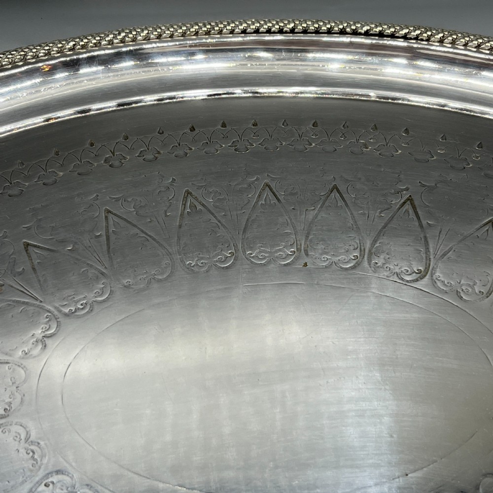 A large Victorian oval silver-plated serving tray featuring twin carrying handles, a textured rope border, and elaborate floral central engraving. View IX