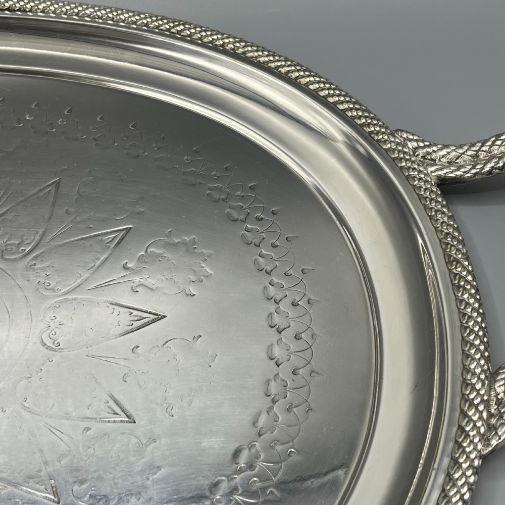 A large Victorian oval silver-plated serving tray featuring twin carrying handles, a textured rope border, and elaborate floral central engraving. View X