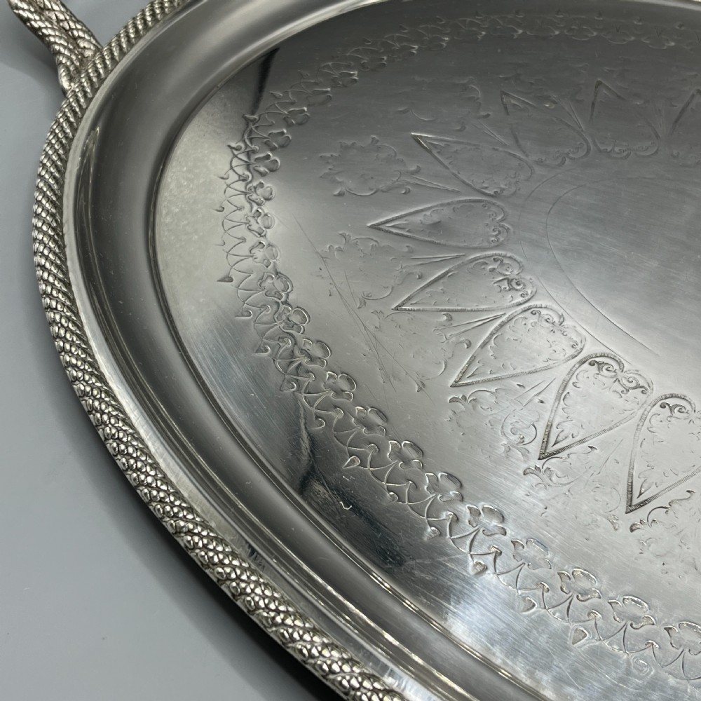 A large Victorian oval silver-plated serving tray featuring twin carrying handles, a textured rope border, and elaborate floral central engraving. View XIII